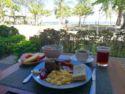 a plate of food on a table with a view of the beach at Hotel M&M Beach House in Coco