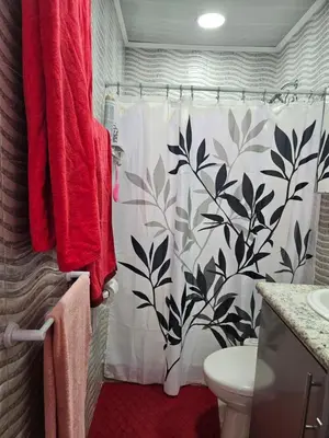 a bathroom with a shower with a flowered shower curtain at Very cozy beautifully designed loft apartment in Coco