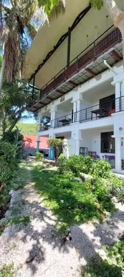 a white building with a balcony and palm trees at noemi apartments samara beach A-2 in Sámara