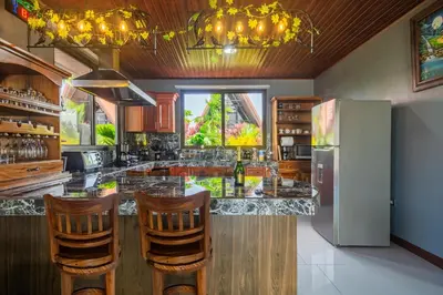a kitchen with a bar with chairs and a refrigerator at Kaluma Villas in San Ramón