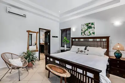 a bedroom with a bed and a chair and a mirror at Stylish Home with Chic Decor, Luxury Amenities & Tropical Outdoor Oasis with Sparkling Private Pool in Brasilito