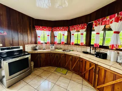 a kitchen with wood paneling and red and white curtains at Cabañas del Norte in Fortuna