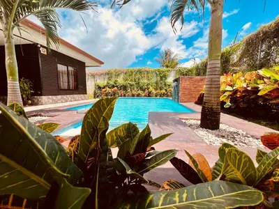 a villa with a swimming pool and palm trees at Cabañas del Norte in Fortuna