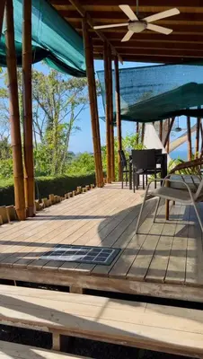 a wooden deck with chairs and a ceiling fan at Eden Tica Lodge in Uvita