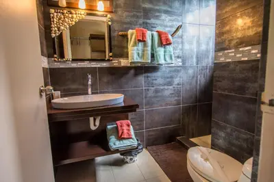 a bathroom with a sink and a toilet and a mirror at Eden Tica Lodge in Uvita