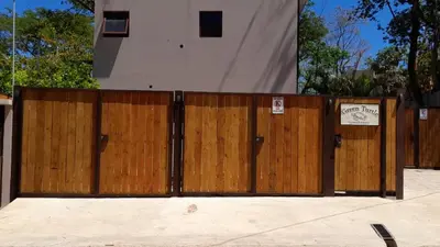 a fence with wooden doors in front of a house at Green Turtle Townhome #1 Private Pool & Garden 300 Mtrs to Beach in Tamarindo