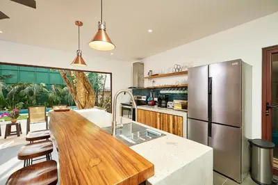 a kitchen with a wooden table and a refrigerator at New Beach House Walk to Tamarindo Beach & Town in Tamarindo