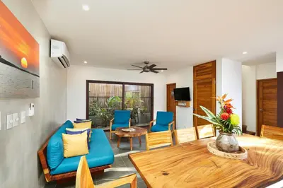 a living room with a table and blue chairs at New Beach House Walk to Tamarindo Beach & Town in Tamarindo