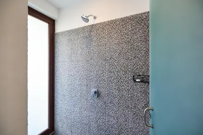 a bathroom with a shower with a tile wall at New Beach House Walk to Tamarindo Beach & Town in Tamarindo