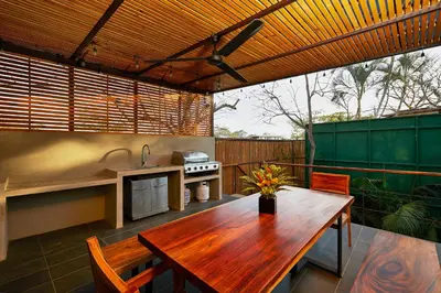 a patio with a wooden table and a kitchen at New Beach House Walk to Tamarindo Beach & Town in Tamarindo