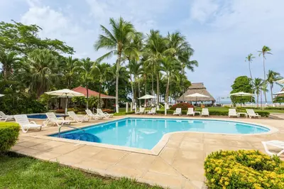 a pool with chairs and umbrellas and palm trees at Hotel & Villas Tangerí in Jacó