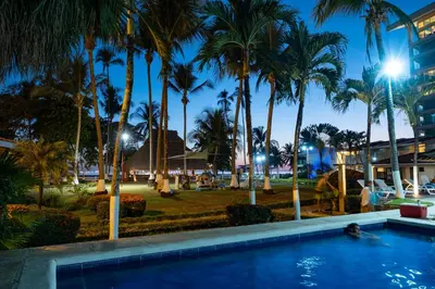 a resort pool with palm trees at night at Hotel & Villas Tangerí in Jacó