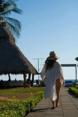 a woman in a white dress and hat walking down a sidewalk at Hotel & Villas Tangerí in Jacó