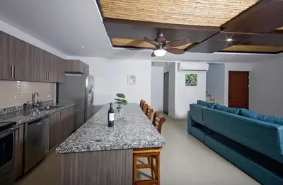 a kitchen and living room with a blue couch and a table at Amazing home with private pool & high-speed Wi-Fi! in Jacó