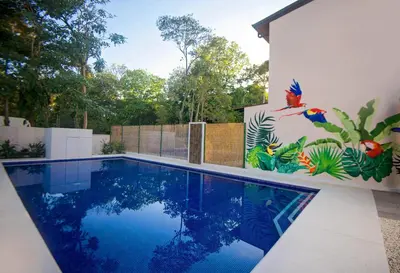 a swimming pool with a mural on the side of a house at Amazing home with private pool & high-speed Wi-Fi! in Jacó