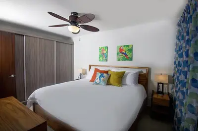 a bedroom with a white bed with a ceiling fan at Amazing home with private pool & high-speed Wi-Fi! in Jacó
