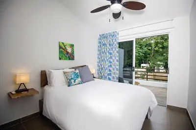 a bedroom with a white bed and a ceiling fan at Amazing home with private pool & high-speed Wi-Fi! in Jacó