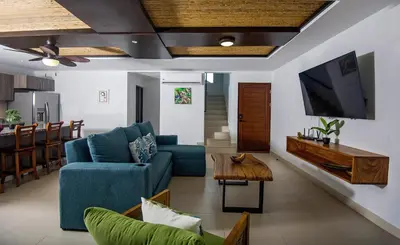 a living room with a blue couch and a tv at Amazing home with private pool & high-speed Wi-Fi! in Jacó
