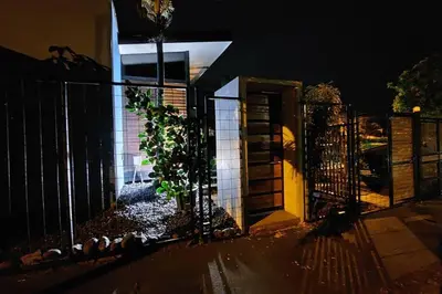a gate to a house with a fence at night at Olly´s House in Turrialba
