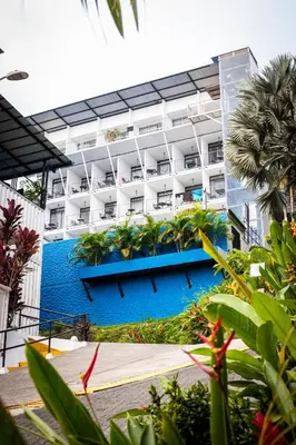 a large white building with a blue swimming pool at El Faro Containers Beach Hotel in Manuel Antonio