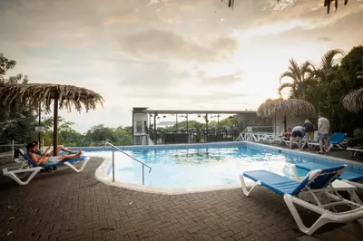 a pool at a resort with people sitting on chairs at El Faro Containers Beach Hotel in Manuel Antonio