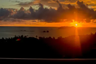 a sunset over the ocean with the sun setting at El Faro Containers Beach Hotel in Manuel Antonio