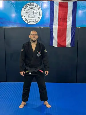 a man is standing in front of a flag at Jungles Edge Hotel, Jiu Jitsu, Muay Thai Retreat Center in Nosara