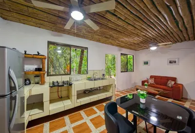 a kitchen and living room with a wooden ceiling at Jungles Edge Hotel, Jiu Jitsu, Muay Thai Retreat Center in Nosara
