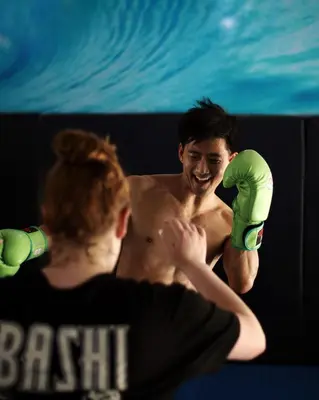 a shirtless man in green shorts standing in the water at Jungles Edge Hotel, Jiu Jitsu, Muay Thai Retreat Center in Nosara