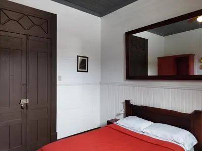 a bedroom with a red bed and a mirror at Casa Aldea Hotel Bed & Breakfast in San José