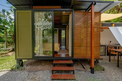 a small house with wooden siding and stairs at Tiny garden house in Turrialba