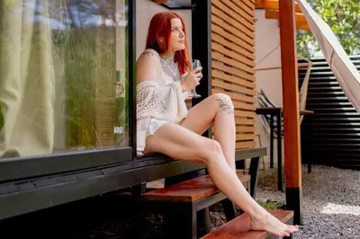 a woman sitting on a bench with a glass of wine at Tiny garden house in Turrialba