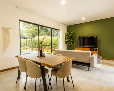a dining room with a table and chairs and a couch at Casa Santa Fe Arenal Volcano in Fortuna