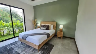 a bedroom with a bed and a large window at Casa Santa Fe Arenal Volcano in Fortuna