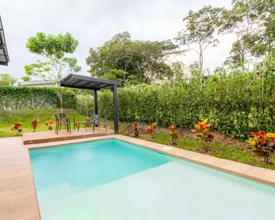 a swimming pool with a pergola next to a garden at Casa Santa Fe Arenal Volcano in Fortuna