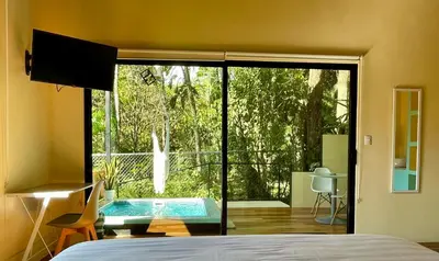 a bedroom with a large sliding glass door with a pool at ChicoRico Studios in Uvita
