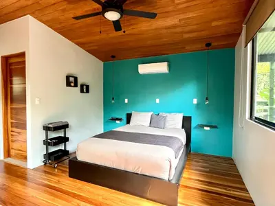 a bedroom with a bed with a blue wall at ChicoRico Studios in Uvita