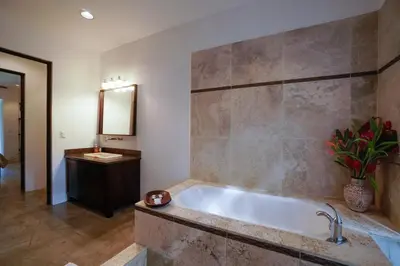 a bathroom with a tub and a sink and a mirror at Makara Resort 5 Bedrooms in Uvita