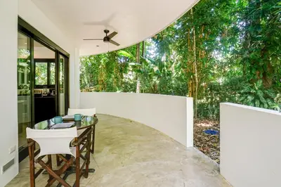 a dining room with a glass table and white chairs at Makara Resort 5 Bedrooms in Uvita