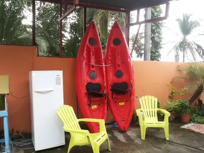 two red kayaks next to two chairs and a refrigerator at Hotel La Uvita in Puerto Limón