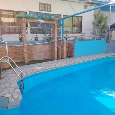 a large swimming pool in a building with a fence at Hotel La Uvita in Puerto Limón