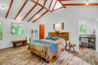 a bedroom with a king sized bed and wooden floors at Lost Pools Bungalows in Ojochal