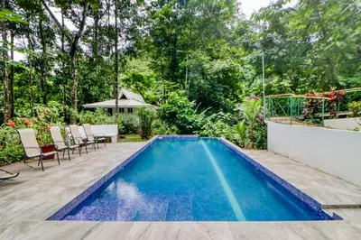 a swimming pool in a backyard with chairs and a table at Lost Pools Bungalows in Ojochal