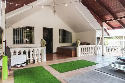 a living room with a couch and a green rug at Mai Ke Kai Surf House in Tamarindo