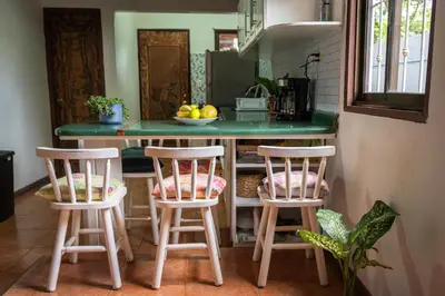 a kitchen with two bar stools and a green counter at Mai Ke Kai Surf House in Tamarindo