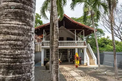 a house with palm trees in front of it at Mai Ke Kai Surf House in Tamarindo
