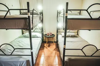 two bunk beds in a room with a table at Mai Ke Kai Surf House in Tamarindo