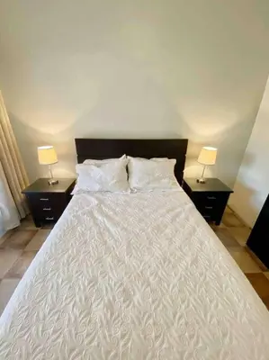 a bedroom with a white bed with two nightstands and two lamps at Beach Bliss - 1BR Villa with Pool 2 blocks from ocean in Jacó
