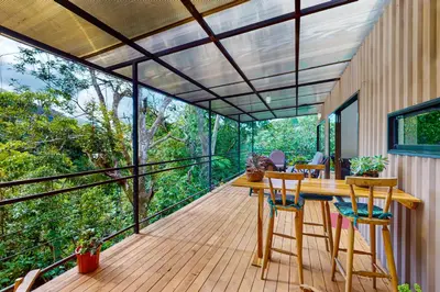 a room with a wooden deck with a table and chairs at Aqua Tarrazu in Santa Cruz