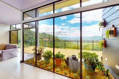 a living room with a large window with a view at El Portal Tarrazu in Santa Cruz